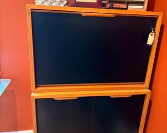 Mid-century wood cabinet with black panel doors, framed art and CD racks on top