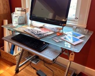 All-in-one desktop computer on glass-top metal desk with keyboard