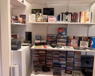 Closet shelving filled with books, CDs, DVDs and media collection, red suitcase