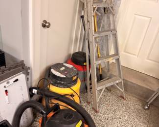 Shop vacuum, aluminum step ladder and power tools in garage