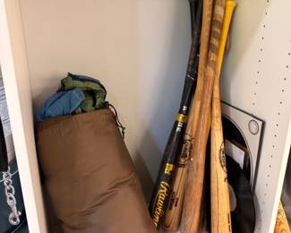 Vintage wooden baseball bats and heavy punching bag in closet