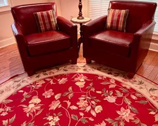 Pair of red leather pub chairs. Round floral area rug on red background.