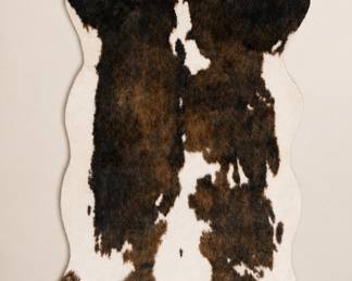 AllModern Epic Performance hand-hooked faux cowhide rug featuring a realistic animal print design in rich brown, black, and ivory tones. Contemporary statement rug with soft texture and organic styling, ideal for layered modern, western, rustic, or eclectic interiors. Dimensions available upon request.