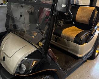 Yamaha gas-powered golf cart featuring custom two-tone seating, upgraded wheels, windshield, overhead storage, and premium canopy enclosure. Clean well-maintained condition with comfortable seating and stylish Village-ready appearance. Great for neighborhood cruising, recreation, or everyday community transportation.