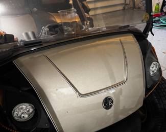 Yamaha gas-powered golf cart featuring custom two-tone seating, upgraded wheels, windshield, overhead storage, and premium canopy enclosure. Clean well-maintained condition with comfortable seating and stylish Village-ready appearance. Great for neighborhood cruising, recreation, or everyday community transportation.