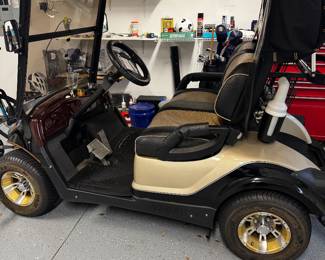 Yamaha gas-powered golf cart featuring custom two-tone seating, upgraded wheels, windshield, overhead storage, and premium canopy enclosure. Clean well-maintained condition with comfortable seating and stylish Village-ready appearance. Great for neighborhood cruising, recreation, or everyday community transportation.