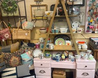 vintage pink desk, ladder shelf, vintage bowls, purses, framed concert posters, plates