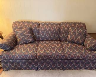 Patterned upholstered couch with rolled arms, skirted base, and matching accent pillows. Great statement piece for den, sitting room, bedroom or eclectic decor. 