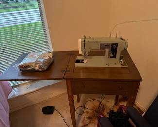 Vintage sewing machine in wood cabinet with fold-out work surface. Classic functional/decorative piece for sewing, crafting or vintage home decor. 