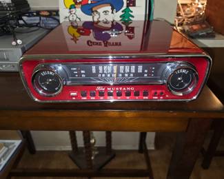 This is an ION Audio Ford Mustang LP, a red, 4-in-one music system designed to look like the dashboard of a 1965 Ford Mustang.Multi-Functionality: It features a 3-speed belt-drive turntable, an AM/FM radio with a speedometer-style dial, a USB input for recording vinyl to a flash drive, and an auxiliary input