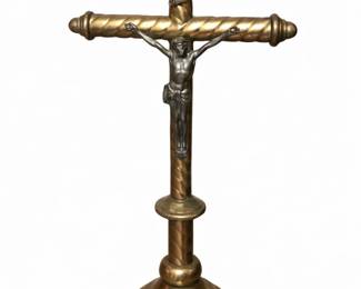 Antique Brass Crucifix with Tiered Base Beautiful antique brass crucifix featuring a finely detailed figure of Jesus mounted on a cross with a twisted, rope‑style design along the beams. The INRI banner sits above the figure, adding classic devotional symbolism. The brass shows a warm, aged patina that highlights the sculpted details and gives the piece an authentic vintage presence.  The crucifix stands on a tiered circular base, sturdy and well‑balanced, making it ideal for display on a table, altar, or shelf.  Condition: Excellent; rich patina, crisp detailing, and strong structural integrity.
