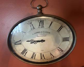 Vintage French‑Style Wall Clock – “Galerie du Gaston” Charming oval wall clock with a classic French design, featuring bold Roman numerals and ornate black hands. The face reads “GALERIE du GASTON, 798 Boulevard Raspail, 1885”, evoking the elegance of late‑19th‑century Paris. The clock’s metallic frame and top ring give it a pocket‑watch silhouette, adding a touch of antique sophistication.  Perfect as a statement piece for a study, hallway, or vintage‑inspired décor.  Condition: Excellent; fully intact with light wear consistent with age.