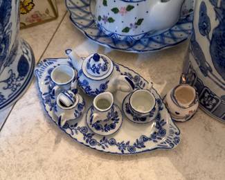 Miniature Blue & White Porcelain Tea Set on Tray A delicate miniature tea service set presented on a matching scallop-edged oval tray, featuring: Pieces included: Teapot with lid, creamer, sugar bowl, and two teacups with saucers β all on a coordinating tray Pattern: Classic blue and white with hand-painted rose and leaf garland motifs Style: Delft-inspired / Chinoiserie cottage Material: Porcelain