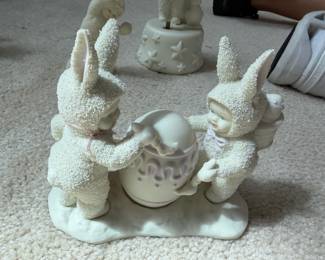 Department 56 Snowbunnies Easter Figurine A charming Easter counterpart to the Snowbabies line, featuring: Subject: Two large Snowbunnies (rabbits in textured snow-white suits with tall bunny ears) flanking a Snowbaby, all gathered around a large decorated Easter egg with lavender/purple swirl detailing Characters: Two bunnies with pink ribbon accents + one cherubic Snowbaby with blue eyes in the center Base: Smooth white snow-drift oval shared base Egg Detail: Large smooth egg with soft purple/lavender decorative swirl pattern β beautifully rendered Material: Bisque porcelain with signature granulated snow texture on the bunny/baby suits Finish: Matte white with soft pastel accent colors