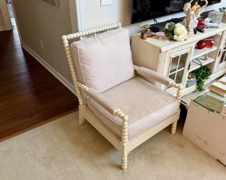 Spindle/Spool Accent Chair A charming and on-trend accent chair in the popular spool/bobbin style, featuring: Frame: Cream/antique white painted wood with classic spool-turned spindle detailing along the back rail, arms, and legs β a hallmark of this style Cushions: Loose seat and back cushions in a soft blush pink/mauve fabric β plush and generously sized Arms: Flat padded arm rests with spool-turned supports beneath Legs: Turned spool-style front legs matching the overall design Style: Cottage / Farmhouse / Shabby Chic β the spool chair design is very popular and currently highly sought after (seen frequently from brands like Pottery Barn, Ballard Designs, and similar) Material: Painted wood frame; upholstered cushions