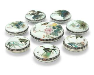 1030 A group of eight Chinese enameled porcelain seal boxes Late Qing Dynasty/Republic Era (1644-1949) Five with red stamped Jiangxi mark; three with blue painted Hongxian mark; three inscribed to lid Comprising seven qianjiangcai boxes and one polychrome, the larger and three smaller decorated with birds and floral motifs, four depicting trees or boats 8 pieces Largest: 1.5" H x 3.875" Dia.; Each smaller: 1.25" H x 2.75" Dia. Estimate: $1,500 - $2,500