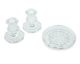 1391 A set of Baccarat glass 'Rosace' coasters and 'Regence' candlesticks Late 20th century Each with etched factory mark Comprising three pairs of 'Regence' candlesticks and three 'Rosace' wine bottle/decanter coasters, each housed in original box with foam inserts 9 pieces Coasters: 5.375" Dia.; Candlesticks: 3.375" H x 3.375" Dia.; Largest box: 4.5" H x 10.25" W x 7" D Estimate: $300 - $500