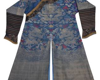   Back to catalog 1354 A Chinese blue and gilt thread brocade Dragon robe Late Qing dynasty or later The long robe in silk, cotton, and gilt-toned thread, the multicolor brocade depicting seven dragons with embroidered eyes surrounded by stylized clouds, flames and multiple auspicious motifs and symbols, the hem and each sleeve edge with motifs depicting waves and deep water, with long striped fabric sleeves with multicolor brocade 'horse-hoof' cuffs, side fastening and inner brocade panel with a dragon motif, split center seams at front and back, and lined in bright blue fabric, with custom-made wall mount for hanging 2 pieces 53.5" H x 26.5" W at underarms; sleeve cuff to collar: 40" L Estimate: $1,500 - $2,500