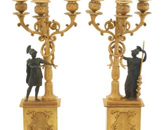 1313 A pair of Empire parcel gilt bronze figural candelabra Pierre-Philippe Thomire (1751-1843), early 19th century One impressed: THOMIRE A PARIS Each with patinated Roman figure beside a standard with laurel wreath issuing scrolling foliate arms terminating in four lights, above an architectural base mounted at front with an armorial 2 pieces Each: 21" H x 8" W x 5.75" D Estimate: $4,000 - $6,000