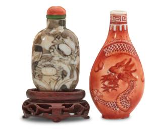1131 Two Chinese porcelain snuff bottles 19th/20th century Comprising one iron red enameled porcelain snuff bottle depicting a dragon and one with enhanced crab design raised on a carved wood stand 2 pieces Dragon: 3" H x 1.625" W x 0.75" D; Crab: 2.625" H x 1.375" W x 0.625" D Estimate: $1,000 - $1,500