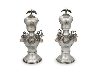 1244 A pair of Continental sterling silver Rimonim Late 19th/early 20th century Each appears unmarked, XRF tested for sterling Each Torah scroll finial decorated with openwork scroll medallions, with dragon-form accents and bird finial, mounted with bells, later in-filled with plaster 2 pieces Taller: 9.125" H x 4.875" Dia. Estimate: $1,000 - $2,000