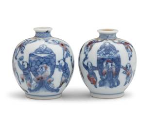 1129 A near pair of Chinese 'One Hundred Boys' porcelain snuff bottles 19th/20th century Each bearing an apocryphal blue underglaze reign mark for Yongzheng Period (1722-1735) Each with blue underglaze on white with iron red accents 2 pieces Each: 2.125" H x 1.875" Dia. Estimate: $1,200 - $1,800