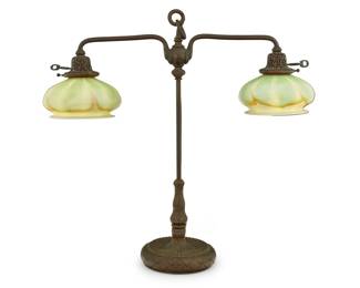 1297 A Tiffany Studios patinated bronze student lamp and Quezal shades Early 20th century Base impressed: TIFFANY STUDIOS NEW YORK / 318; each shade marked: Quezal The standard issuing an adjustable height arm with two lights, each mounted with matching pulled feather glass shades, electrified 23.5" H x 24.5" W x 7.5" D Estimate: $1,000 - $1,500