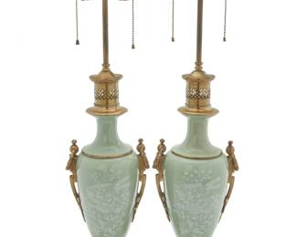 1258 A pair of brass mounted pâte-sur-pâte porcelain lamps Mid-20th century One with applied retail sticker: Warren Kessler / NEW YORK Each urn decorated with floral motifs on pale green, converted to a two-light lamp and mounted with brass foliate accents with garland ring handles, raised on an architectural base, electrified 2 pieces Each: 31.5" H x 8.5" W x 6.25" D Estimate: $400 - $600