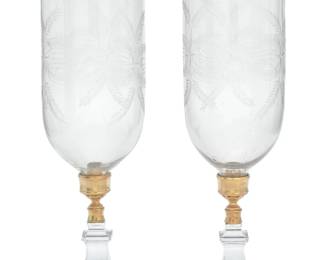1053 A pair of engraved and molded glass and gilt metal storm candlesticks 19th/early 20th century Each with bell-shaped engraved glass shade over a gilt-metal socket on a molded glass base with lemon squeezer underside 2 pieces Each: 20.375" H x 7.5" Dia. Estimate: $300 - $500
