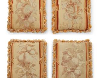 1304 Four Aubusson tapestry cushions The tapestry panels, 19th century Comprising four tapestry border panel fragments, each featuring cascading fruit, flower, and foliage designs in pale beiges and browns, with darker ombré stripes to side edges, and each backed with pale pink velveteen and edged with tonal passementerie tassel trim 4 pieces Each: 14.5" H x 12" W approximately Estimate: $400 - $600