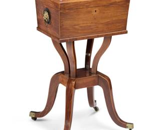 1336 A Regency rosewood teapoy Early 19th century The edges with inlaid trim, the locking lid opening to reveal four wood tea caddies centered by a tin lidded compartment, the casket mounted with opposed brass lion mask ring handles, raised on shaped supports and four sloping legs terminating in brass casters 32.25" H x 19.5" W x 17.5" D Estimate: $500 - $700