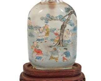 1136 A Chinese inside painted rock crystal 'One Hundred Boys' snuff bottle With cyclical date to 1903 Depicting boys at play beneath a tree, raised on a carved wood stand Bottle: 2.875" H x 1.5" W x 0.75" D; Stand: 0.875" H x 2.125" W x 1.125" D Estimate: $2,000 - $3,000