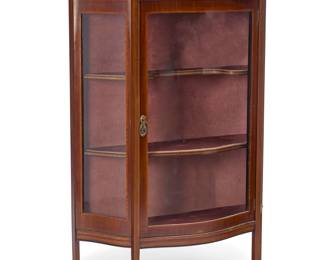 1383 An Edwardian mahogany vitrine Circa 1920 With applied metal plaque: Allen & Appleyard, / ARTISTIC FURNISHERS / RENSHAW STREET & BOLD STREET / LIVERPOOL The case with inlaid trimming and painted with bellflower garlands, with curved glass front locking door, revealing a velvet-lined interior and two shelves, raised on tapered legs with front spade feet 62.5" H x 41" W x 16.25" D Estimate: $1,000 - $2,000
