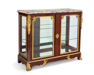 1072 A Louis XV style gilt bronze mounted parquetry rosewood vitrine François Linke (1855-1946), early 20th century Marked under the lock: CT LINKE / SERRURERIE / PARIS With gilt-bronze foliate mounts, trim, and front paw feet, the glazed locking cabinet doors revealing a mirrored back and two glass shelves, surmounted by a marble top 42.5" H x 52.5" W x 20.5" D Estimate: $5,000 - $7,000