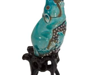 1135 A Chinese porcelain squirrel snuff bottle Kangxi Period (1662-1722) or style Raised on an ebonized carved wood stand Depicting a squirrel grasping a fruiting branch Bottle: 3.25" H x 1.375" W x 1.25" D; Stand: 1.625" H x 1.62" W x 1.375" D; Overall: 4" H Estimate: $1,000 - $2,000