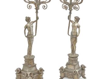 1311 A pair of Empire style silvered metal figural candelabra 20th century Each standard depicting a maiden hoisting five lights, raised on an architectural base with ram heads at corners and hoof feet 2 pieces Each: 42.5" H x 14.5" W x 11.25" D Estimate: $1,000 - $1,500