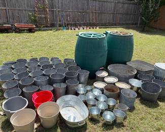 Backyard filled with galvanized steel buckets in all sizes. Four 75 gallon rain barrels 