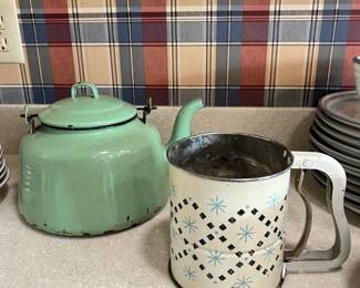 Retro kitchenware classics featuring a mint green enamelware kettle and an aluminum flour sifter with a starburst design.