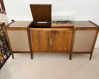 Vintage 3-Piece Console Stereo System: A stunning mid-century wooden stereo hifi setup featuring a center credenza with a flip-top lid for housing a turntable, flanked by two matching large floor-standing speaker cabinets with woven cane grilles.