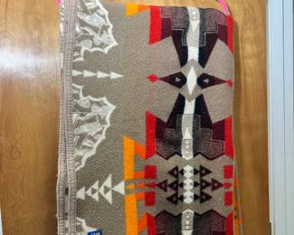 An authentic vintage Beaver State by Pendleton 100% wool Indian trade blanket showing a vibrant orange, red, and charcoal geometric pattern.