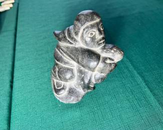 A beautifully detailed, authentic hand-carved black soapstone Inuit/Eskimo sculpture of a figure cradling an animal.