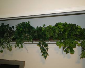 A shelving system just filled with faux plants, and yes, we will display these properly at some point in time