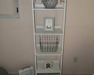 Tall shelving unit with storage drawer on the bottom.  Clock on the floor