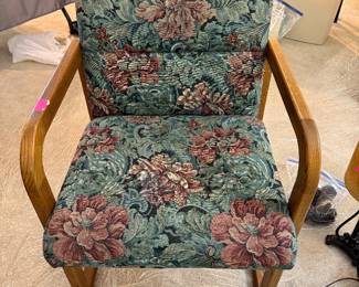 armchair is a mid-century modern design featuring a teak wood frame and floral tapestry upholstery