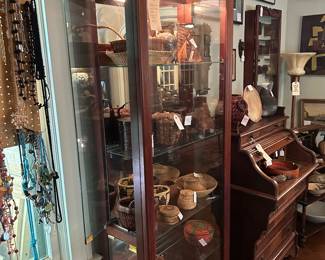 A collection mostly off hand made woven baskets from around the world in a Tall Lighted Curio Display Cabinet with adjustable glass shelves