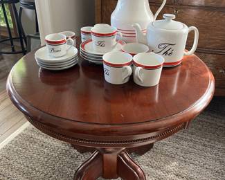 A set of matching teacups and dessert plates, sitting atop a small wooden table.