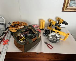 A table of tools, including drills, measuring sticks, flashlights, tape, and a table saw.