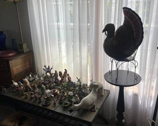 A table of animal figurines, presided over by a large turkey plush. The table is mostly birds, but there are also a few rabbits and elephants.