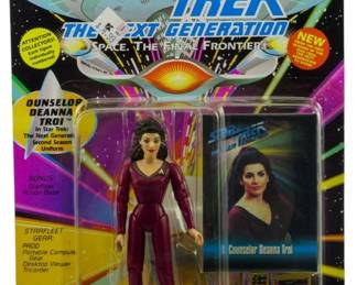 523 - Unopened Star Trek TNG Counselor Troi Figure (Description): Unopened Star Trek The Next Generation action figure in original packaging. The figure depicts Counselor Deanna Troi in her Second Season uniform. Manufactured by Playmates, the package includes bonus Starfleet action base, Starfleet gear including P