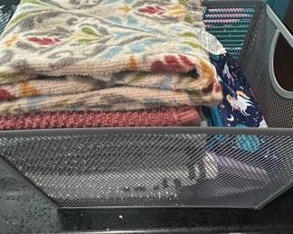 Assorted Towels and Fabric Items in Mesh Basket